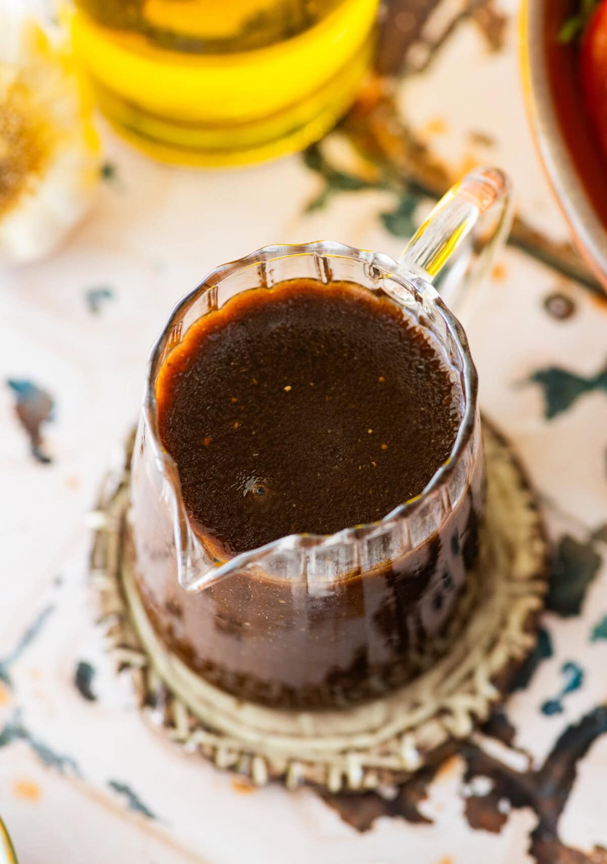 A small glass pitcher of Italian balsamic dressing. 