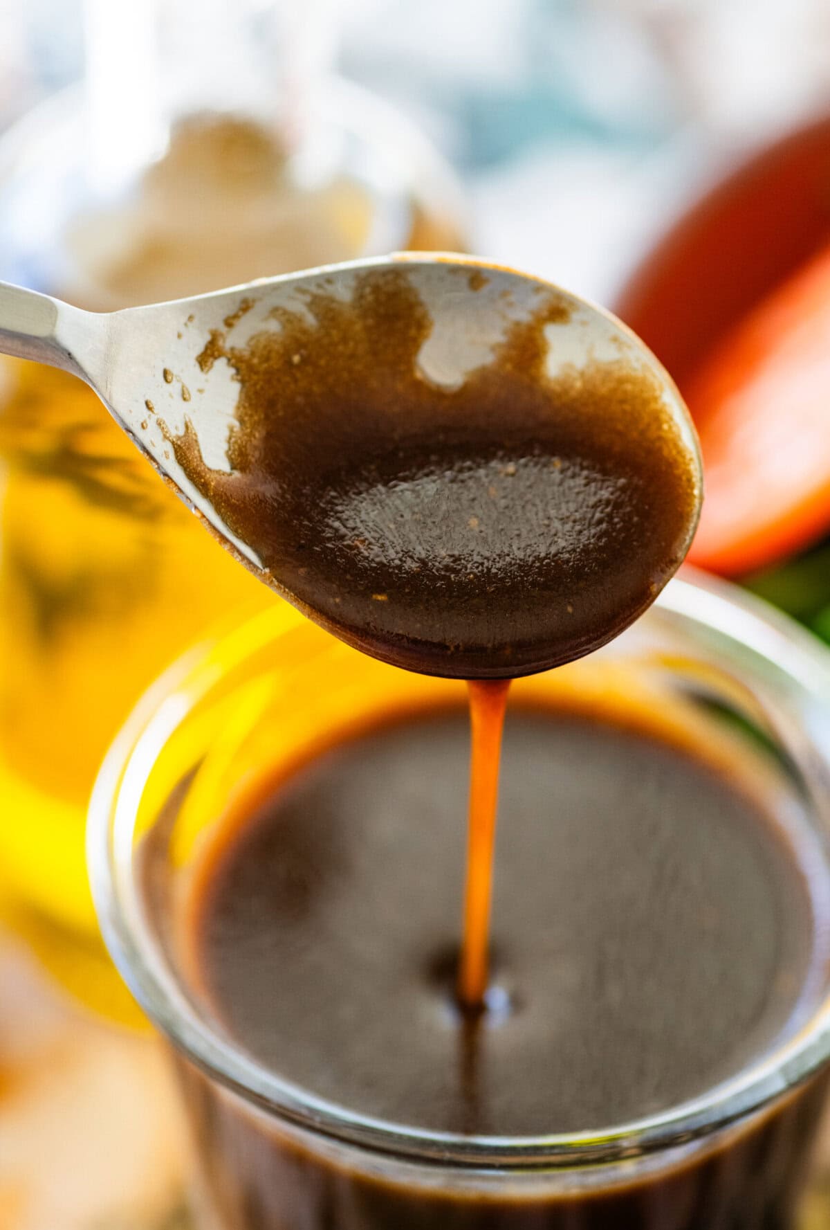 A spoon drizzling some balsamic vinaigrette back into the jar. 