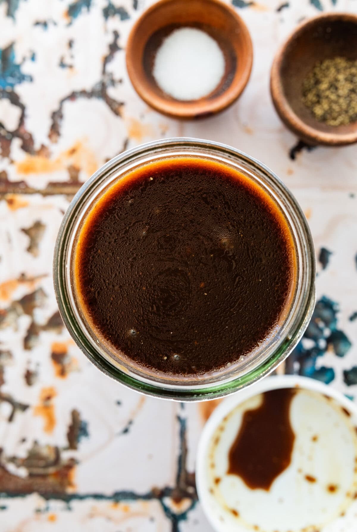 Balsamic dressing mixed in a jar with other ingredients around.