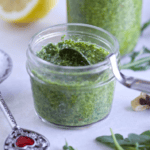 Arugula walnut pesto in a jar with more in the background.