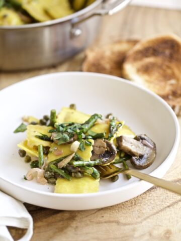 Ravioli Piccata mushrooms and asparagus on a plate with grilled bread