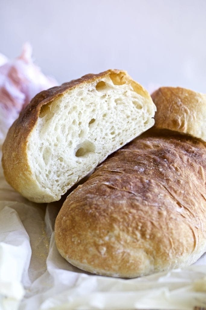 Ciabatta loaves stacked on a parchment paper.