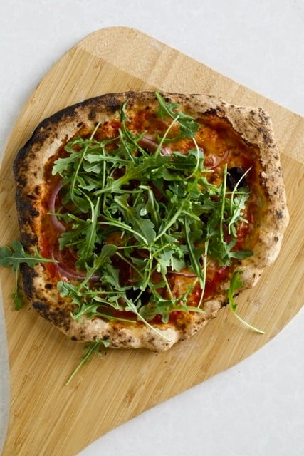 Homemade pizza topped with extra arugula.