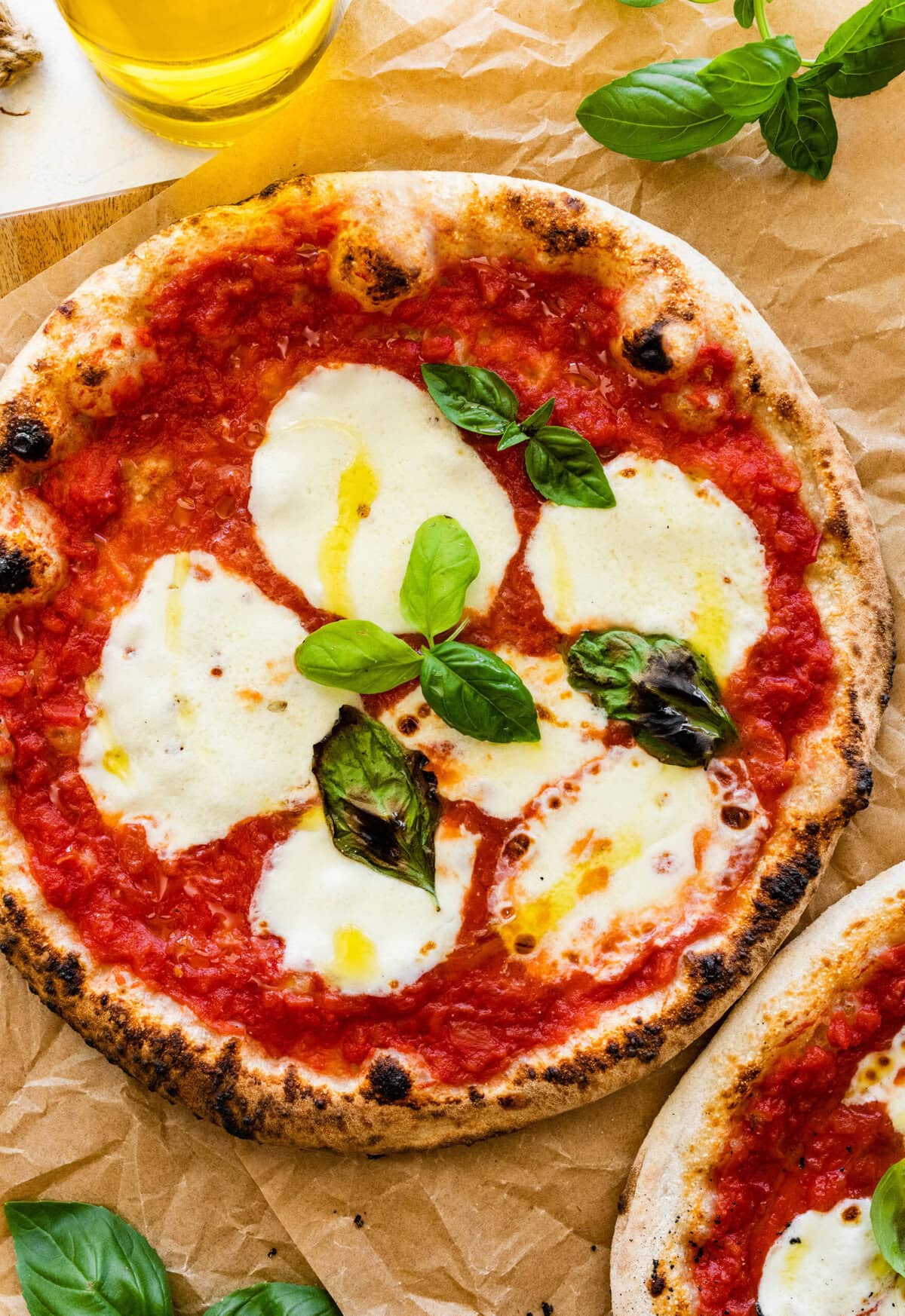 Two pizzas with mozzarella cheese (margherita pizza) and basil leaves