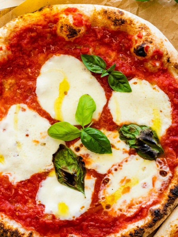 Two pizzas with mozzarella and basil on a wooden table. Neapolitan pizza margherita recipe.
