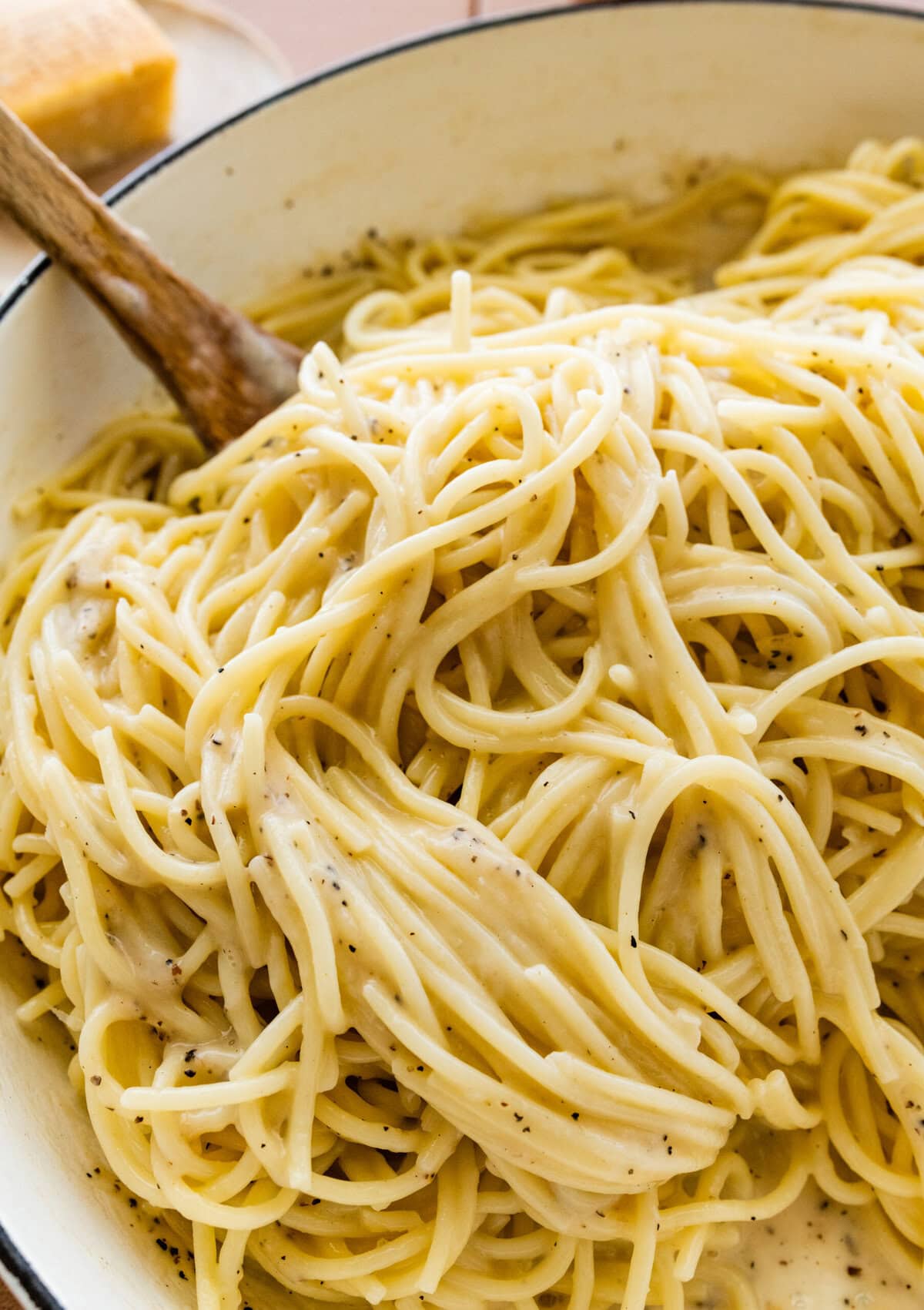 creamy cacio e pepe with a serving spoon in the pan.