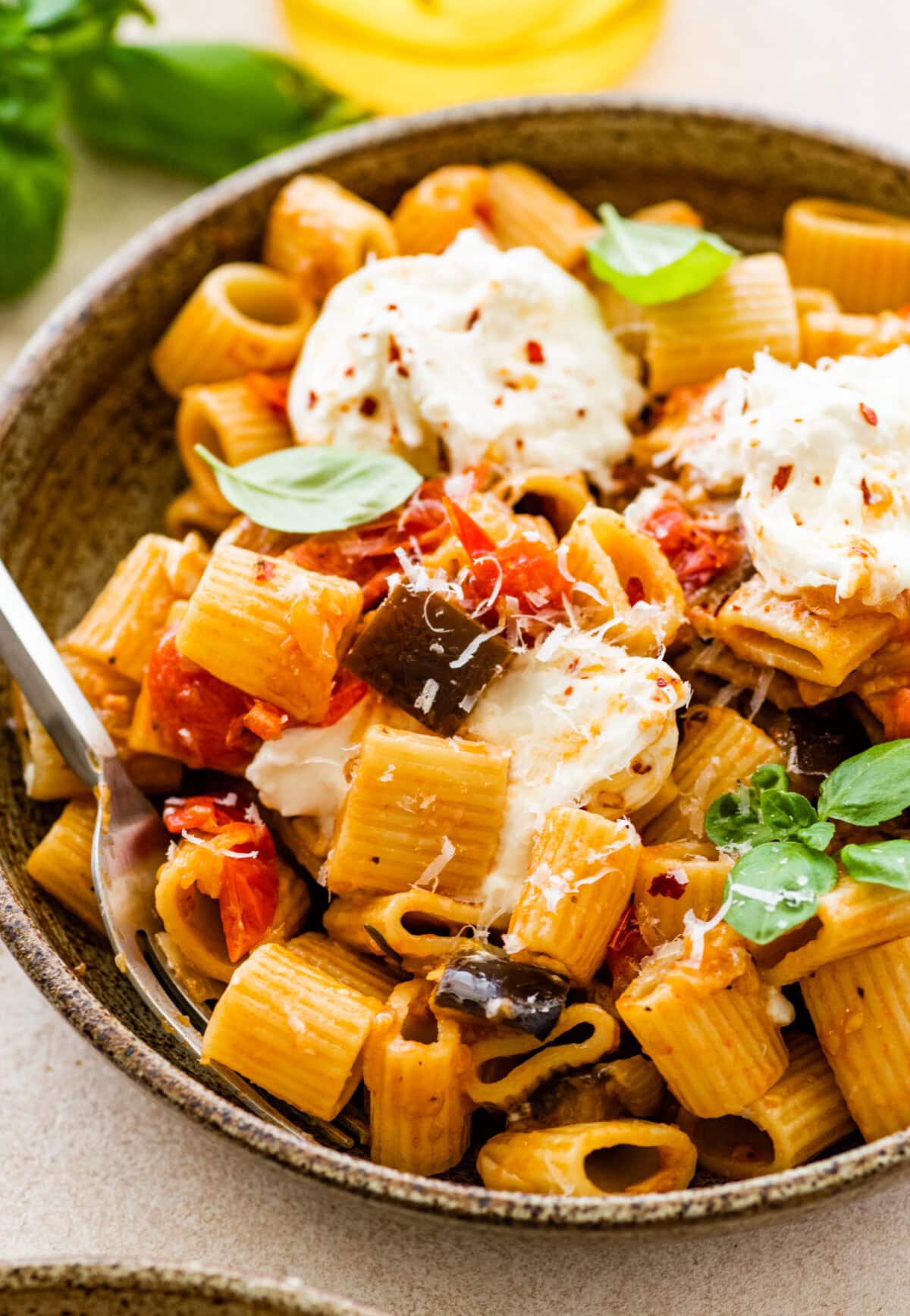 bowl of the eggplant pasta with burrata on top and fork in it.