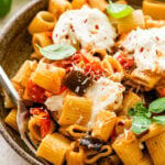 bowl of the eggplant pasta with burrata on top and fork in it.