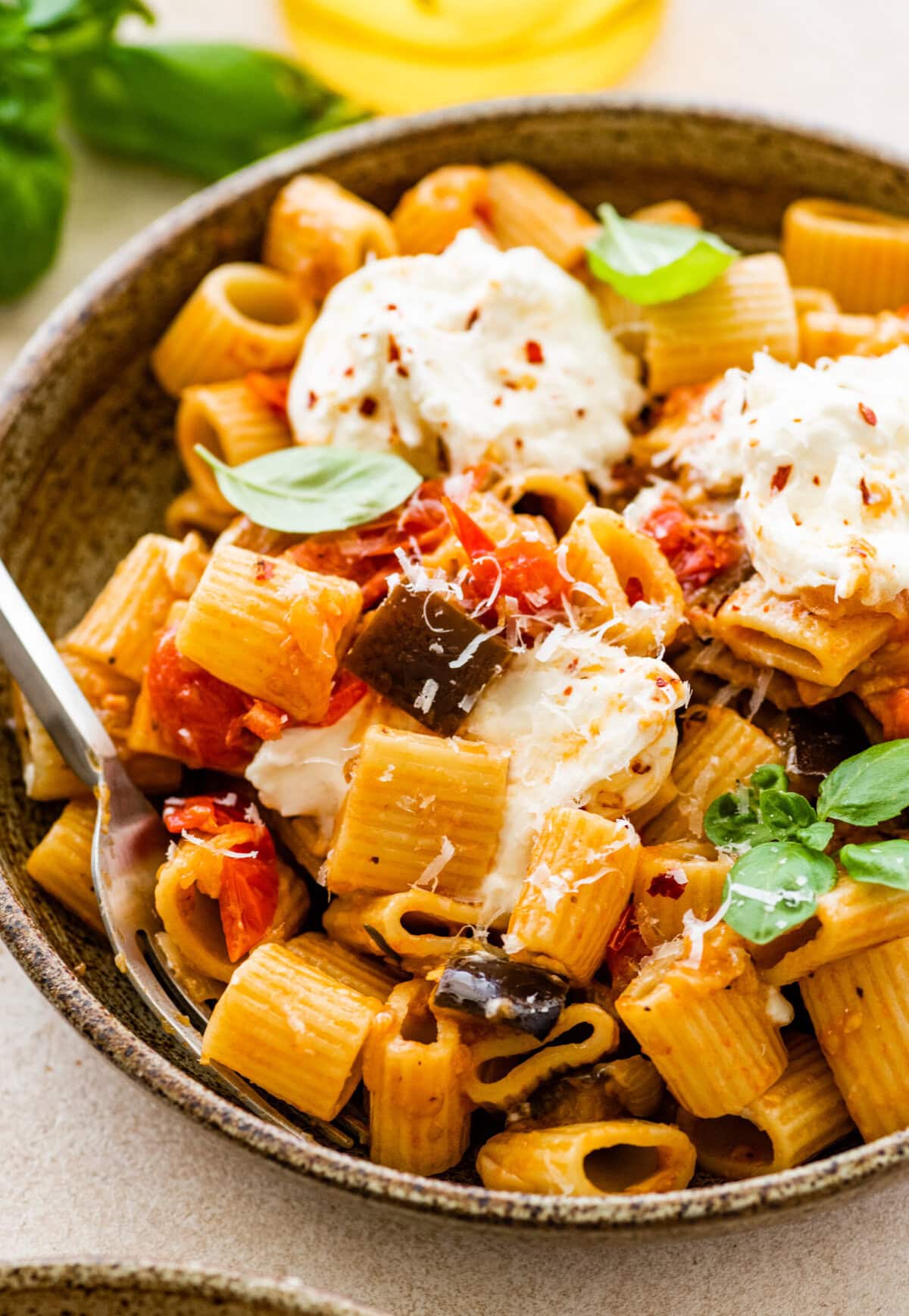 bowl of the eggplant pasta with burrata on top and fork in it.