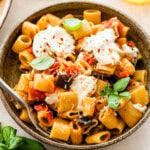 bowl of the eggplant pasta with burrata on top and fork in it.
