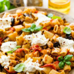 plated eggplant pasta with basil and burrata on top.