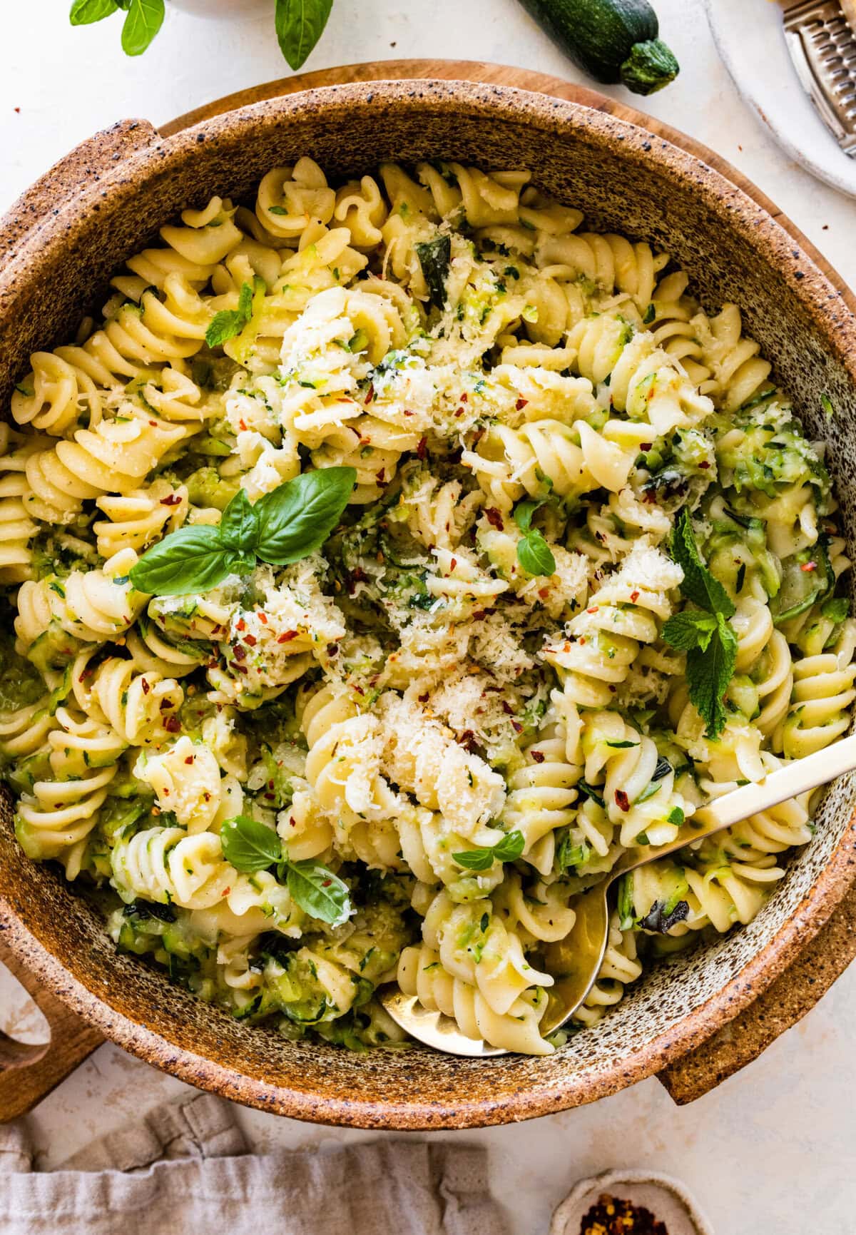 Pasta with zucchini and cheese in a bowl with a fork in it.