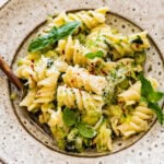 Pasta with zucchini and cheese in a bowl with a fork in it.