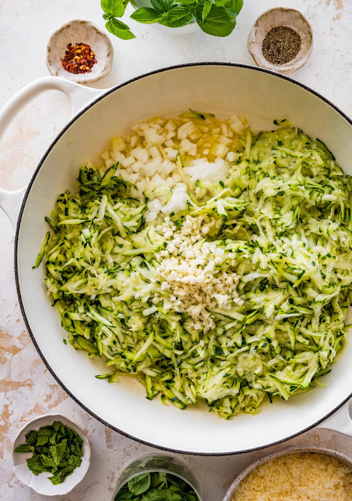A pan filled with olive oil, zucchini, cheese and herbs.