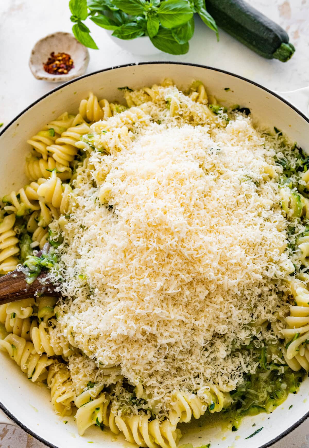 Pan of zucchini pasta with lots of parmigiano cheese on the top.