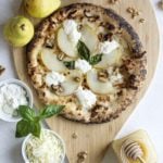 Pear, honey, and walnut cheese pizza on a wooden board.
