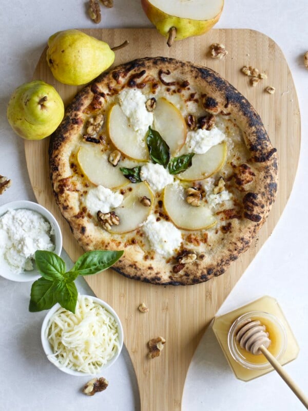 Pear, honey, and walnut cheese pizza on a wooden board.