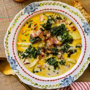 A bowl of potato kale soup with a red and white napkin to the side.