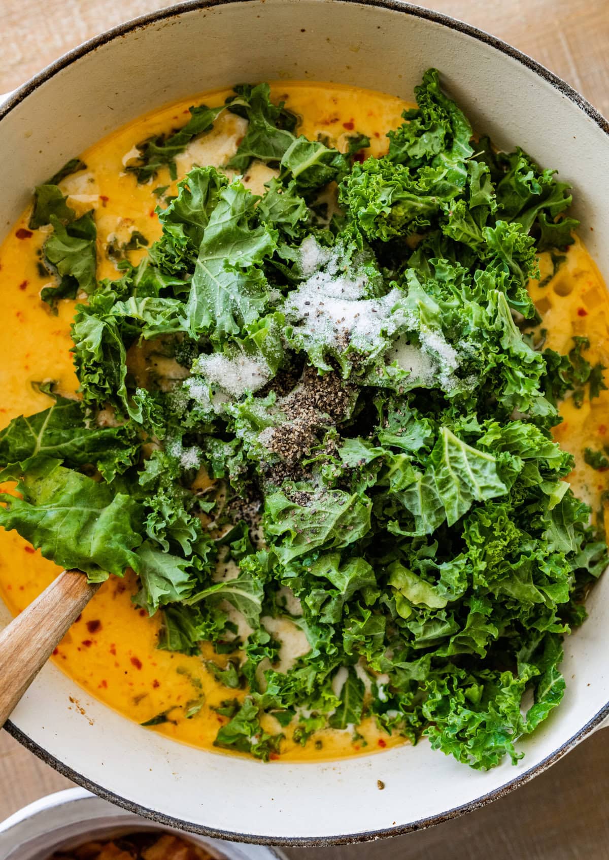 Kale added to the pot of soup.