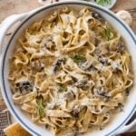 creamy pappardelle pasta with mushrooms in a large pot with more ingredients nearby.