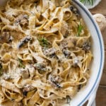 creamy pappardelle pasta with mushrooms in a large pot with more ingredients nearby.