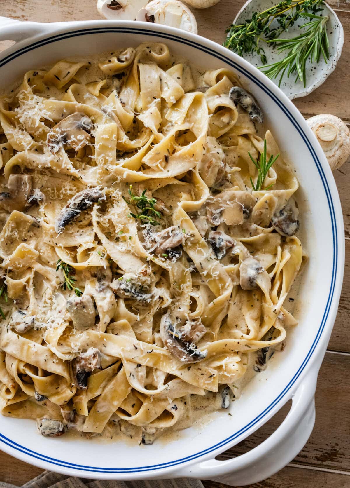 creamy pappardelle pasta with mushrooms in a large pot with more ingredients nearby.