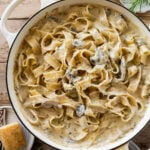 creamy pappardelle pasta with mushrooms in a bowl with ingredients nearby.
