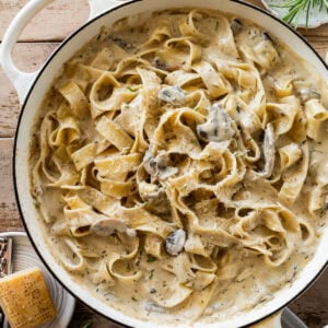 creamy pappardelle pasta with mushrooms in a bowl with ingredients nearby.