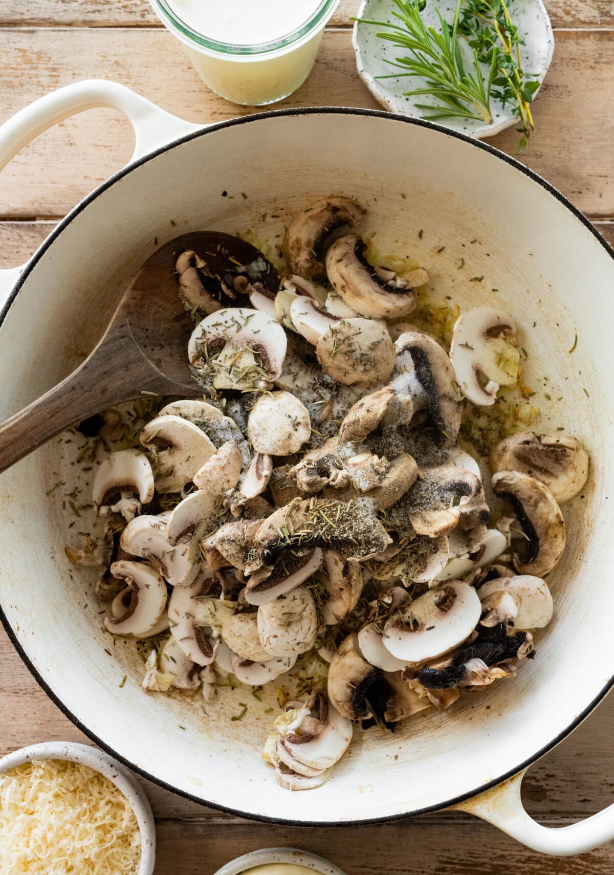 mushrooms added to a large pot with garlic, onions, and olive oil, and more ingredients nearby.