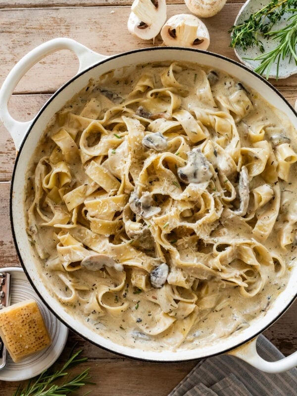 creamy pappardelle pasta with mushrooms in a large pot with more ingredients nearby.