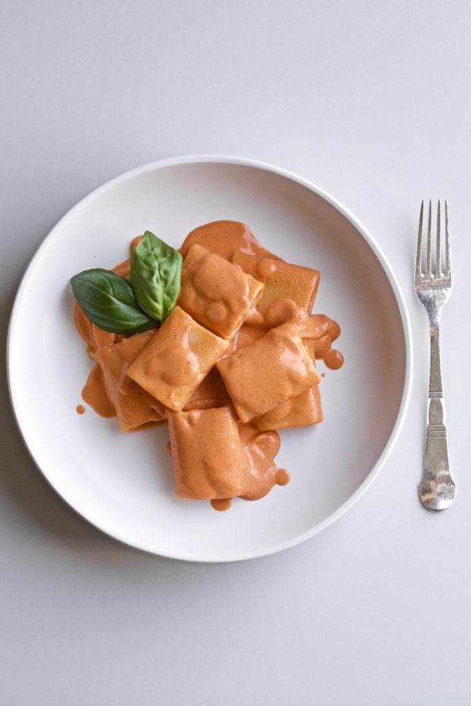 red pepper pasta on a white plate with a fork.