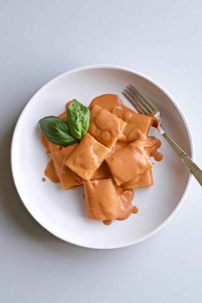 red pepper pasta on a white plate with a fork.