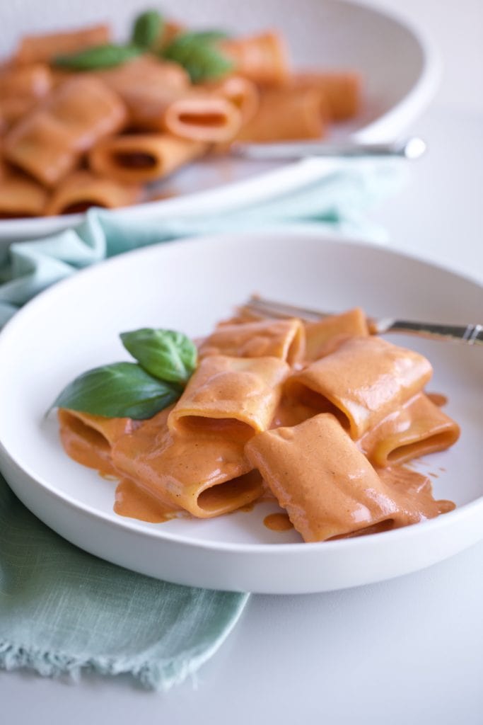 red pepper pasta on a white plate with a fork.