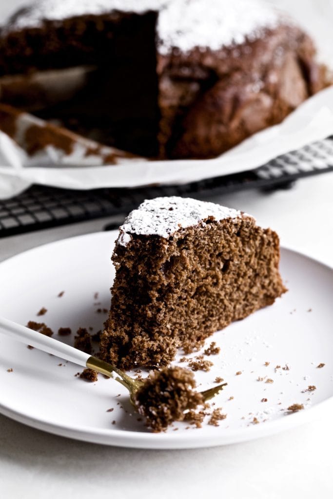 Slice of Italian flourless chocolate torte on a plate with a fork that has a bite.