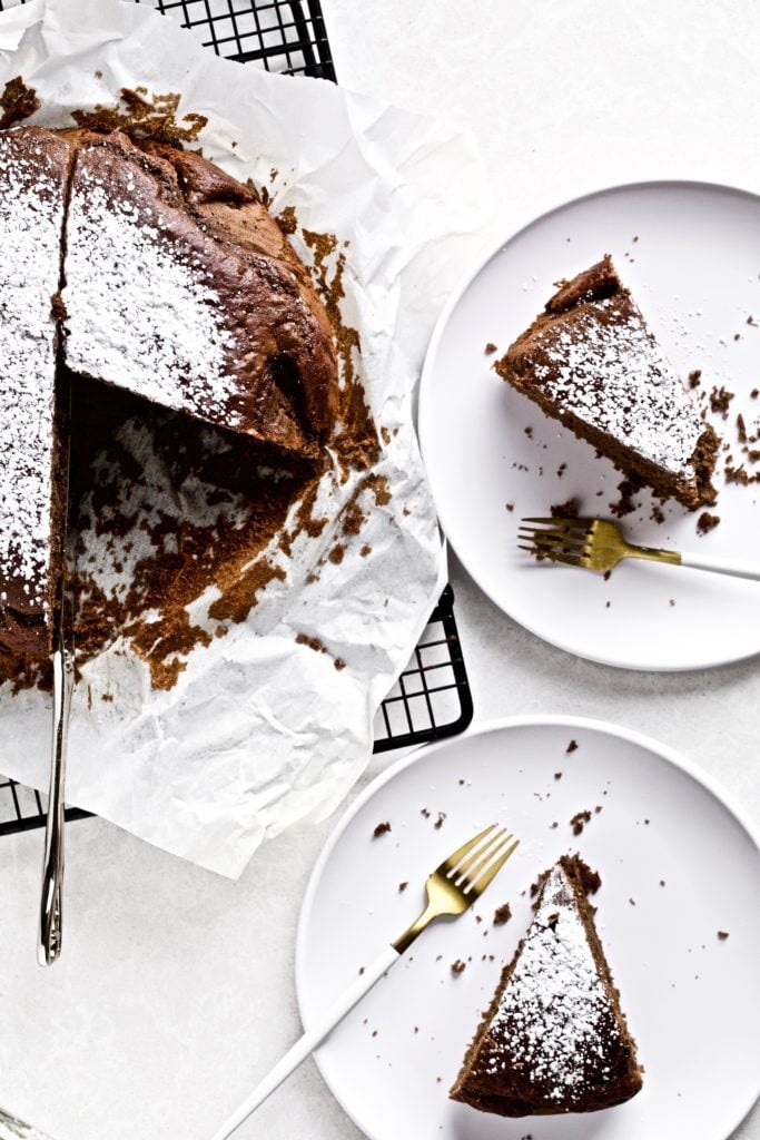 Slices of Italian flourless chocolate torte on plates next to the rest of the torte.