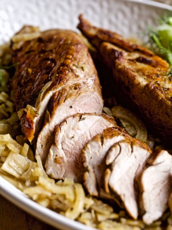 Tray with a partially-sliced pork tenderloin with fennel.