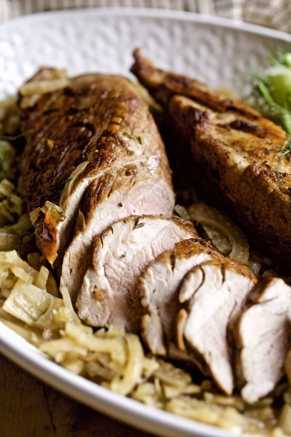 Tray with a partially-sliced pork tenderloin with fennel.