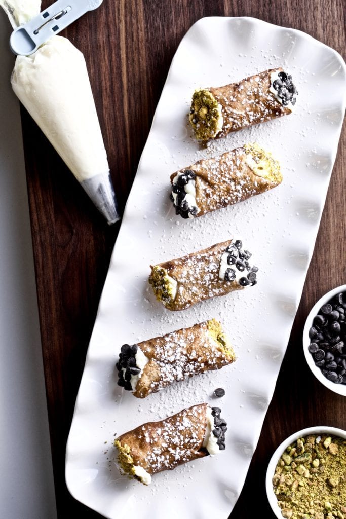 Cannoli on a white plate and a piping bag.