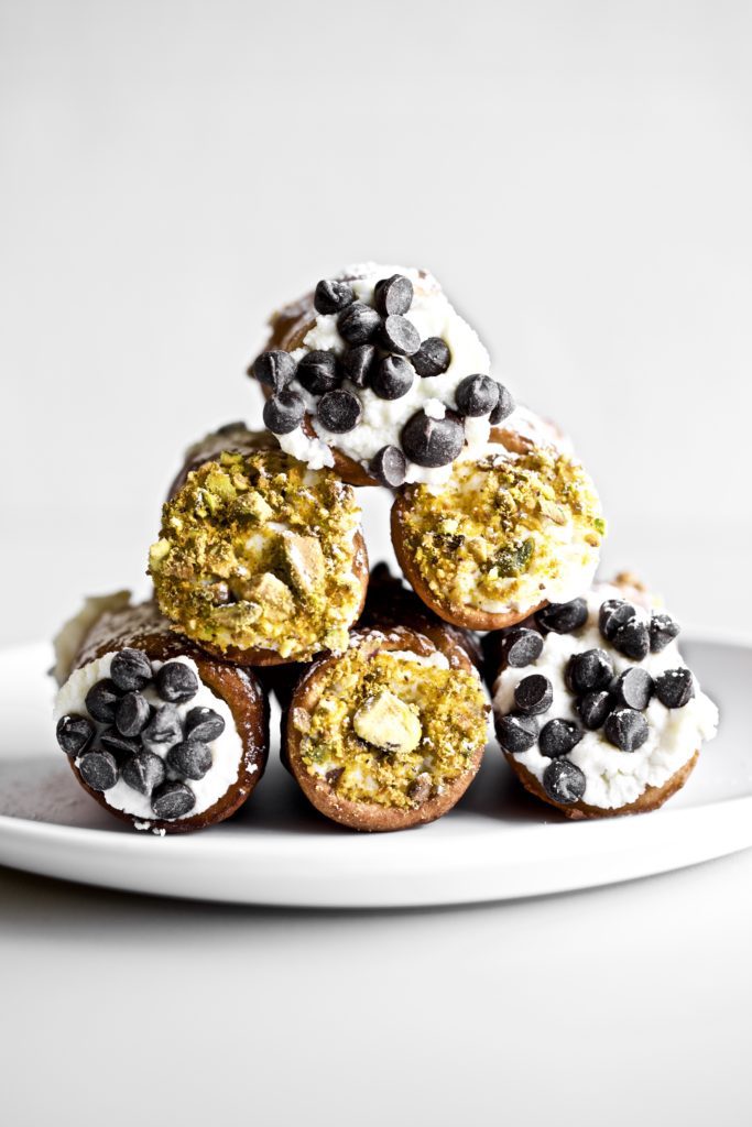 Cannoli stacked on a white plate.