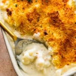 scooping a portion of the creamy cheesy cauliflower casserole.