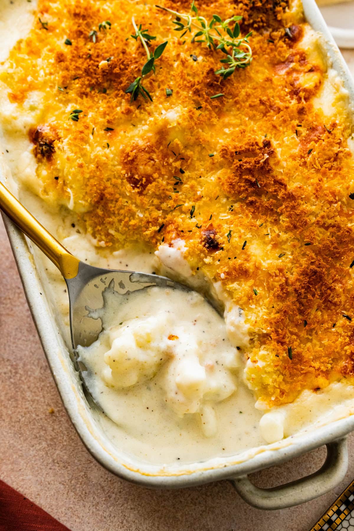 scooping a portion of the creamy cheesy cauliflower casserole.