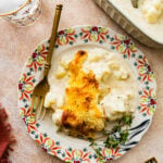 creamy cheesy cauliflower casserole on a plate with a fork next to it ready to eat.