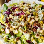 pear gorgonzola salad in a white serving bowl with salad servers near it.