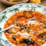 A warm bowl of the tuscan ribollita soup in an old fashioned bowl. Extra freshly grated parm on top for garnish. A spoon in the bowl.