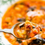 A warm bowl of the tuscan ribollita soup in an old fashioned bowl. Extra freshly grated parm on top for garnish. A spoon in the bowl.