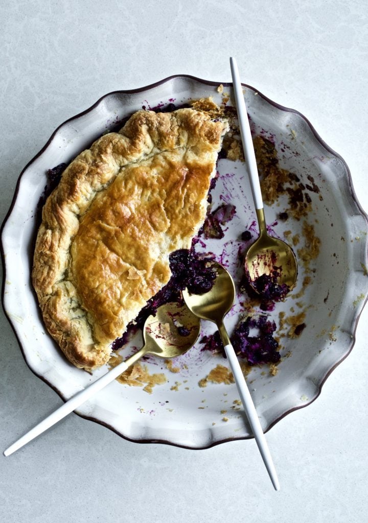 Best Bursting Blueberry pie slice and pie plate with spoons