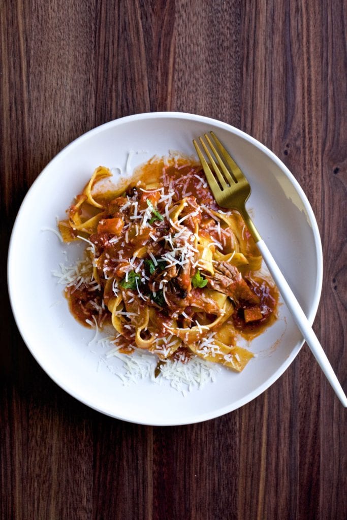 Fork on a plate of beef short rib sauce with pappardelle pasta.