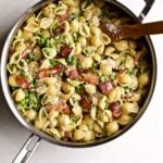 Creamy pasta shells with petite peas and bacon in a skillet pan