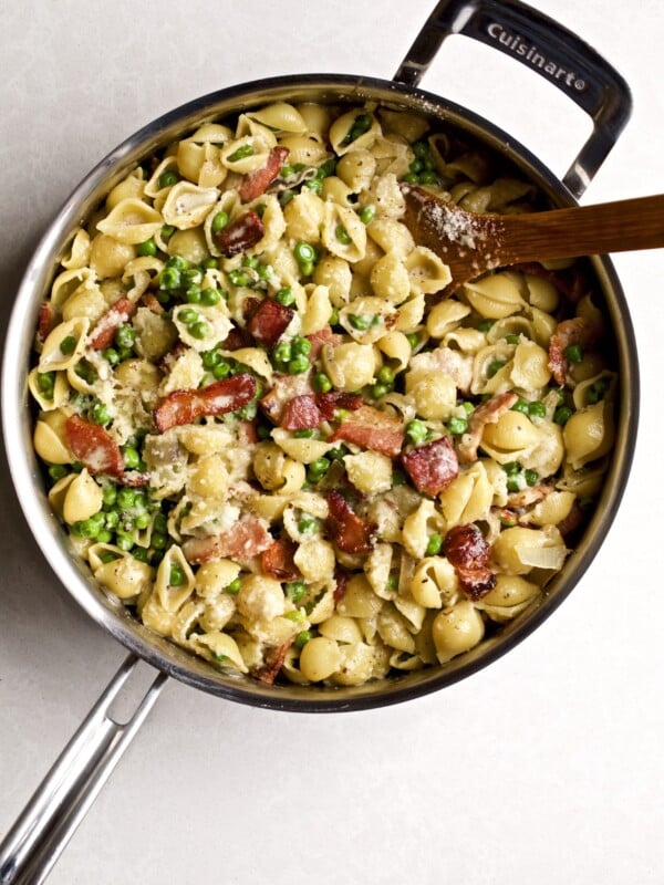 Creamy pasta shells with petite peas and bacon in a skillet pan