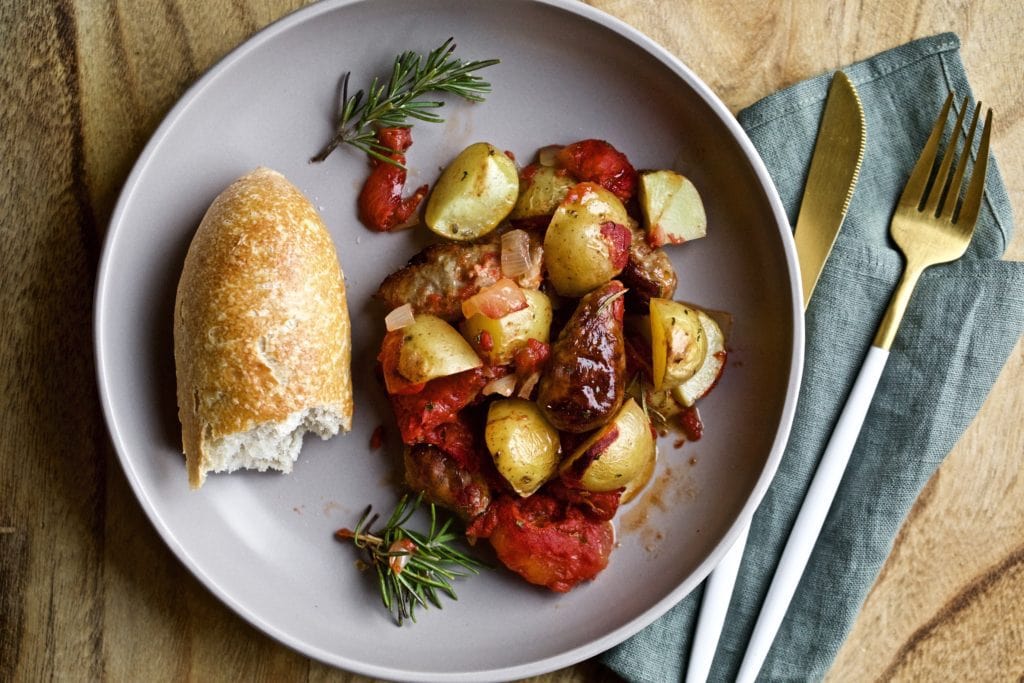 Italian sausage and potatoes on a plate with bread.